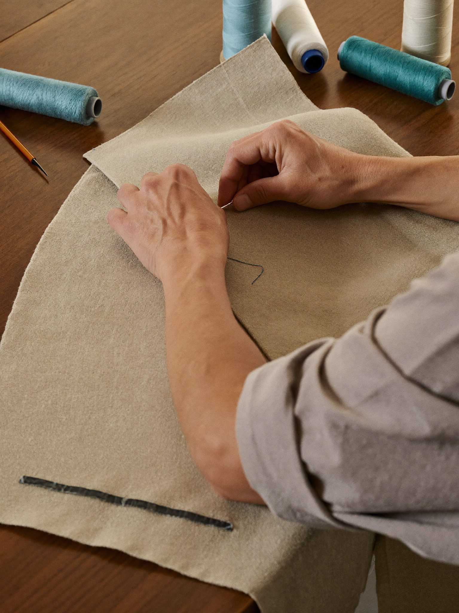 Mãos a coser a bainha de uma camisa numa oficina minhota